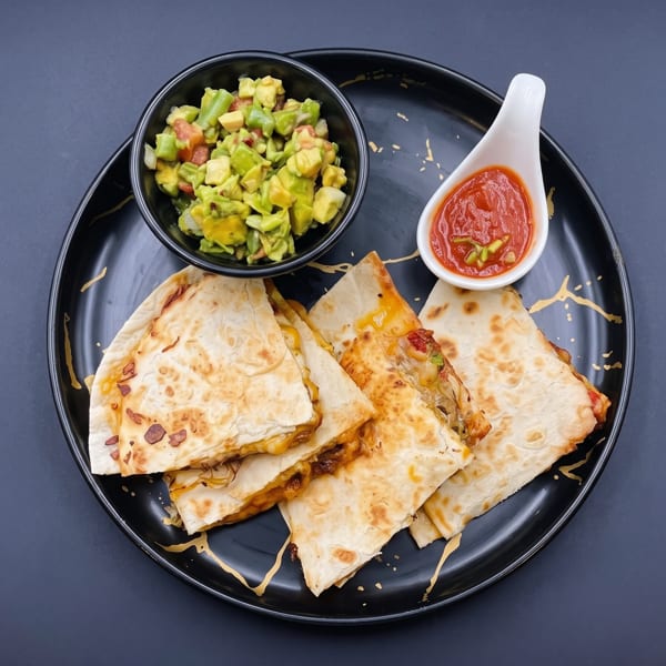 Golden quesadilla triangles with melted cheese, served with fresh guacamole and vibrant red salsa.